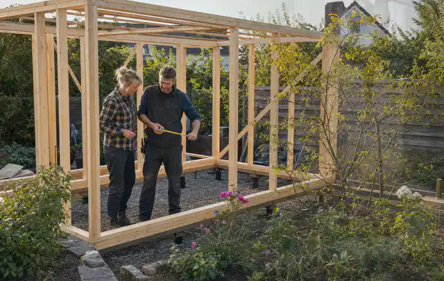 Person plant den Bau eines Gartenhauses auf einer vorbereiteten Fläche; Thema Gartenhaus aus Metall, Schwerpunkt DIY; Kontrolle.