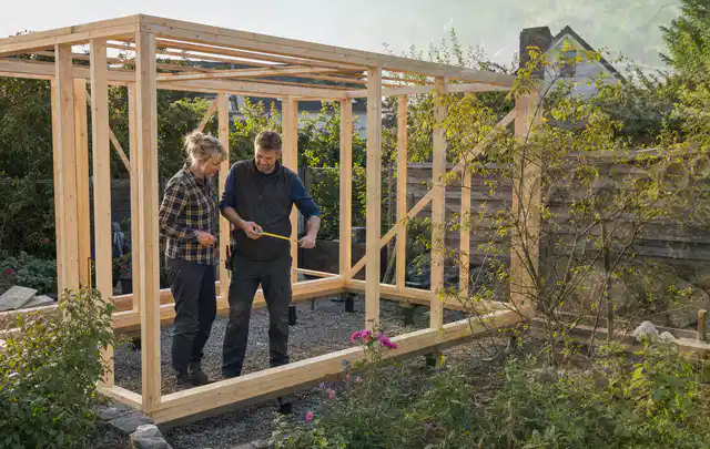 Person plant den Bau eines Gartenhauses auf einer vorbereiteten Fläche; Thema Gartenhaus aus Metall, Schwerpunkt Kosten; Kontrolle.