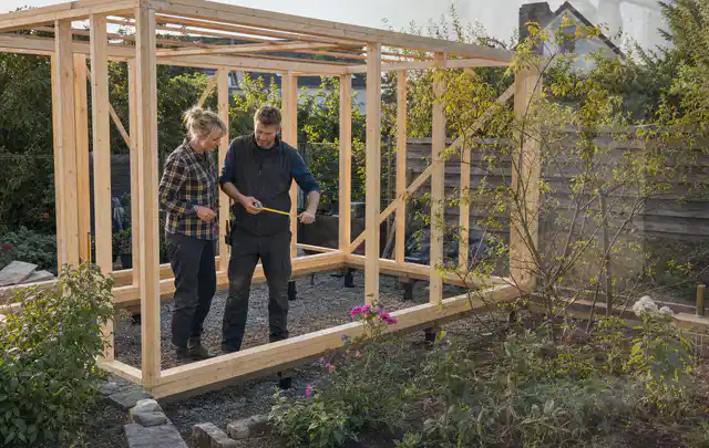 Person plant den Bau eines Gartenhauses auf einer vorbereiteten Fläche; Thema Gartenhaus aus Metall, Schwerpunkt Standort; Praxisalltag.