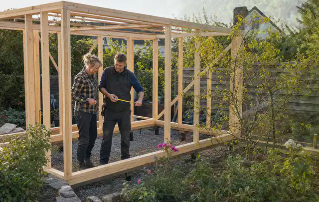 Person plant den Bau eines Gartenhauses auf einer vorbereiteten Fläche; Thema Gartenhaus aus Metall, Schwerpunkt Winterschutz; Ausgangslage.
