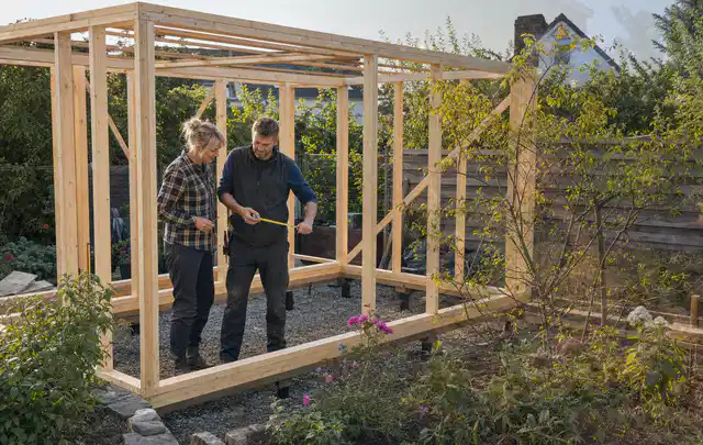 Person plant den Bau eines Gartenhauses auf einer vorbereiteten Fläche; Thema Gartenhaus Dach, Schwerpunkt Aufbau; Ergebnis.