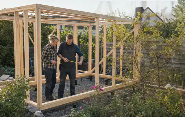 Person plant den Bau eines Gartenhauses auf einer vorbereiteten Fläche; Thema Gartenhaus Fenster, Schwerpunkt Aufbau; Praxisalltag.