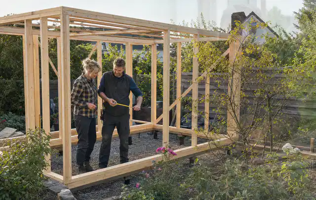 Person plant den Bau eines Gartenhauses auf einer vorbereiteten Fläche; Thema Gartenhaus Fenster, Schwerpunkt DIY; Kontrolle.