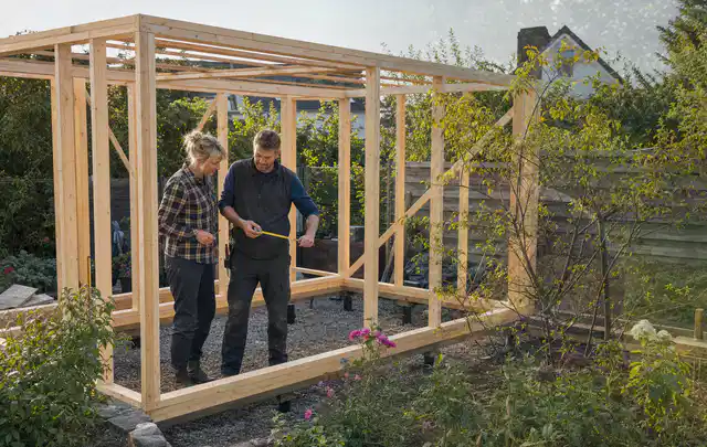 Person plant den Bau eines Gartenhauses auf einer vorbereiteten Fläche; Thema Gartenhaus Fenster, Schwerpunkt Materialwahl; Kontrolle.