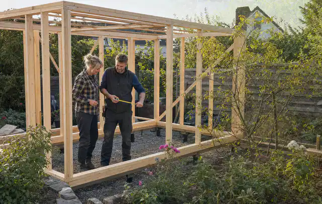 Person plant den Bau eines Gartenhauses auf einer vorbereiteten Fläche; Thema Gartenhaus Fundament, Schwerpunkt Baurecht; Umsetzung.