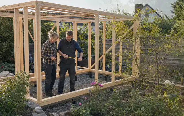 Person plant den Bau eines Gartenhauses auf einer vorbereiteten Fläche; Thema Gartenhaus Fundament, Schwerpunkt Dimensionierung; Ergebnis.