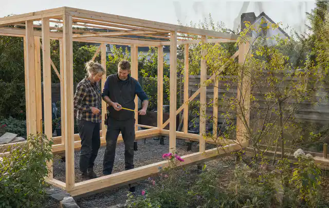 Person plant den Bau eines Gartenhauses auf einer vorbereiteten Fläche; Thema Gartenhaus Fundament, Schwerpunkt Fehlerhilfe; Praxisalltag.