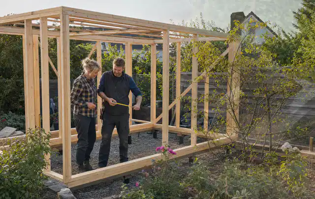Person plant den Bau eines Gartenhauses auf einer vorbereiteten Fläche; Thema Gartenhaus Fundament, Schwerpunkt Gärten mit kleiner Fläche; Ergebnis.
