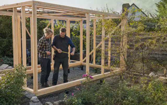 Person plant den Bau eines Gartenhauses auf einer vorbereiteten Fläche; Thema Gartenhaus Fundament, Schwerpunkt Winterschutz; Ergebnis.