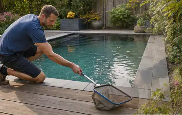 Person entfernt Blätter mit einem Kescher aus einem kleinen Gartenpool; Thema Gartenlounges, Schwerpunkt Gärten mit kleiner Fläche; Kontrolle.