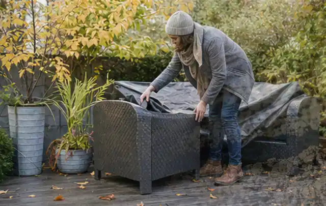 Person deckt Gartenmöbel vor der kalten Jahreszeit sorgfältig ab; Thema Gartenlounges, Schwerpunkt Kaufberatung; Kontrolle.