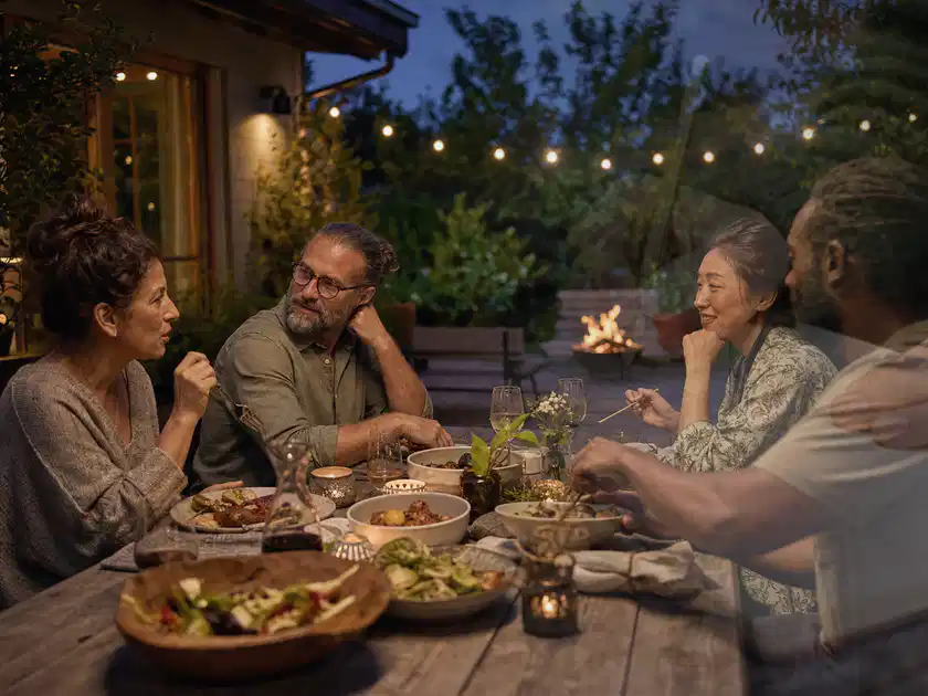 Menschen verbringen einen ruhigen Abend an einem Sitzplatz im Garten; Thema Gartenlounges, Schwerpunkt Vergleich; Titelbild.