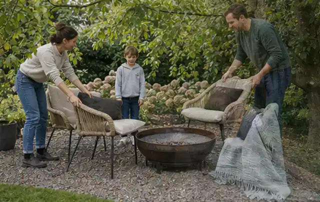Familie stellt wetterfeste Sessel an einem geschützten Sitzplatz im Garten auf; Thema Gartenlounges, Schwerpunkt Winterlager; Umsetzung.