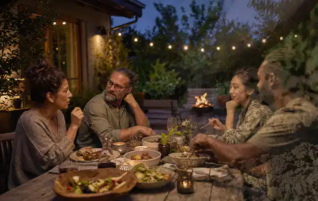 Menschen verbringen einen ruhigen Abend an einem Sitzplatz im Garten; Thema Gartenlounges, Schwerpunkt Winterlager; Praxisalltag.