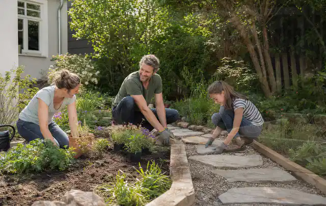 Familie geht auf einem Weg durch einen abwechslungsreich gestalteten Garten; Thema Gartenneuanlage, Schwerpunkt Beleuchtung; Ergebnis.