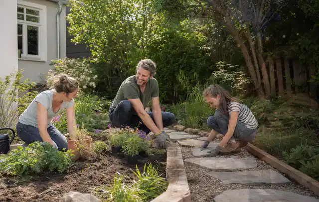Familie geht auf einem Weg durch einen abwechslungsreich gestalteten Garten; Thema Gartenneuanlage, Schwerpunkt Bepflanzung; Kontrolle.