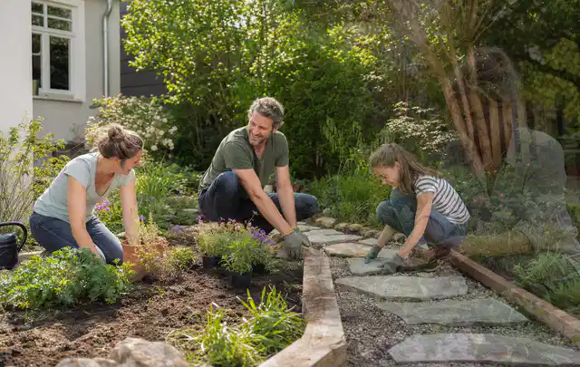 Familie geht auf einem Weg durch einen abwechslungsreich gestalteten Garten; Thema Gartenneuanlage, Schwerpunkt Garten gestalten; Umsetzung.