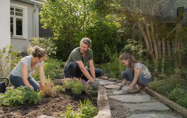Familie geht auf einem Weg durch einen abwechslungsreich gestalteten Garten; Thema Gartenneuanlage, Schwerpunkt Hanglage; Umsetzung.