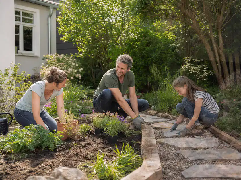 Familie geht auf einem Weg durch einen abwechslungsreich gestalteten Garten; Thema Gartenneuanlage, Schwerpunkt Inspiration; Titelbild.