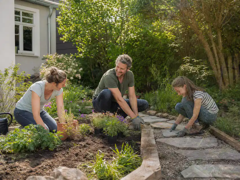 Familie geht auf einem Weg durch einen abwechslungsreich gestalteten Garten; Thema Gartenneuanlage, Schwerpunkt Praxisbeispiele; Titelbild.