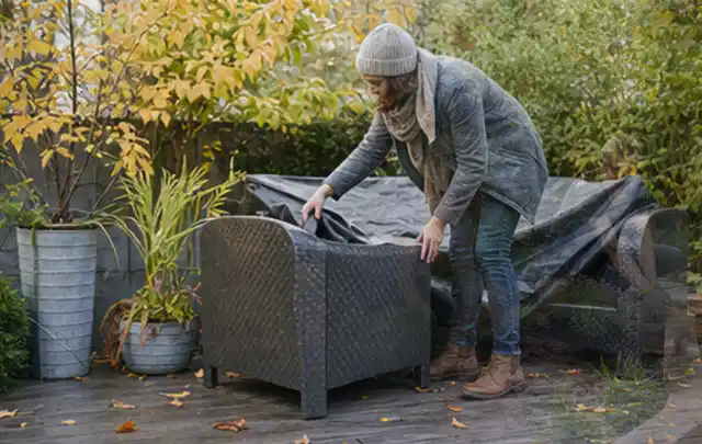 Person deckt Gartenmöbel vor der kalten Jahreszeit sorgfältig ab; Thema Gartenstühle, Schwerpunkt Dimensionierung; Umsetzung.