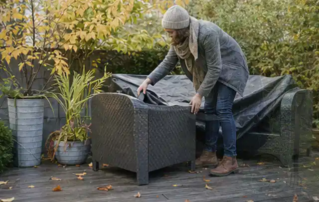 Person deckt Gartenmöbel vor der kalten Jahreszeit sorgfältig ab; Thema Gartenstühle, Schwerpunkt Ersatzteile; Praxisalltag.