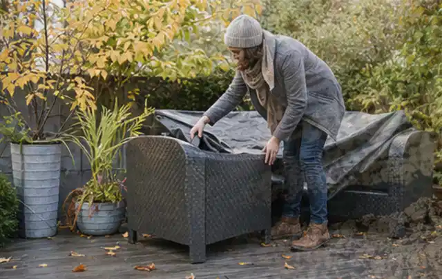 Person deckt Gartenmöbel vor der kalten Jahreszeit sorgfältig ab; Thema Gartenstühle, Schwerpunkt Kaufberatung; Kontrolle.