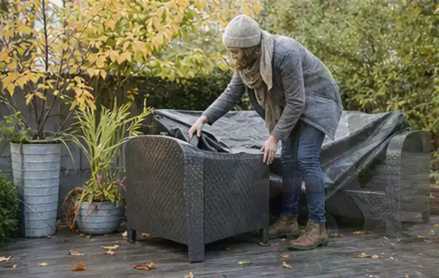 Person deckt Gartenmöbel vor der kalten Jahreszeit sorgfältig ab; Thema Gartenstühle, Schwerpunkt Reparatur; Ausgangslage.