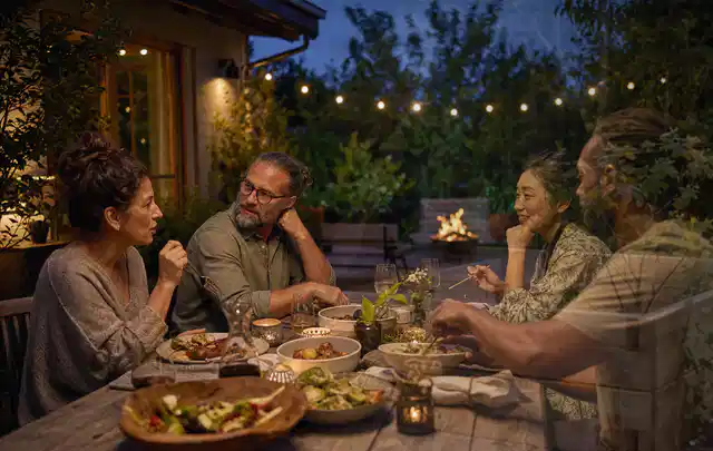 Menschen verbringen einen ruhigen Abend an einem Sitzplatz im Garten; Thema Gartenstühle, Schwerpunkt Sicherheit; Ausgangslage.