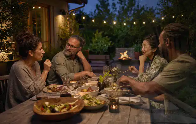 Menschen verbringen einen ruhigen Abend an einem Sitzplatz im Garten; Thema Gartenstühle, Schwerpunkt Systemvergleich; Ausgangslage.