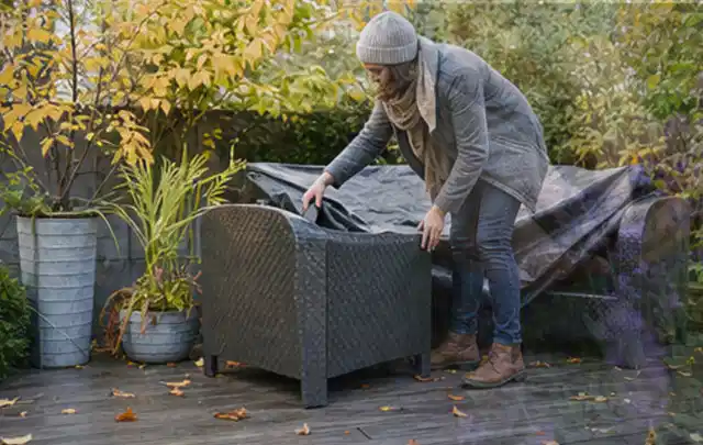 Person deckt Gartenmöbel vor der kalten Jahreszeit sorgfältig ab; Thema Gartenstühle, Schwerpunkt Testkriterien; Kontrolle.
