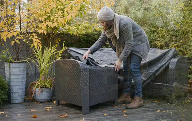 Person deckt Gartenmöbel vor der kalten Jahreszeit sorgfältig ab; Thema Gartenstühle, Schwerpunkt Wartung; Ergebnis.