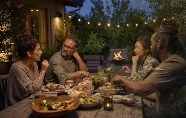 Menschen verbringen einen ruhigen Abend an einem Sitzplatz im Garten; Thema Gartenstühle, Schwerpunkt Winterlager; Praxisalltag.
