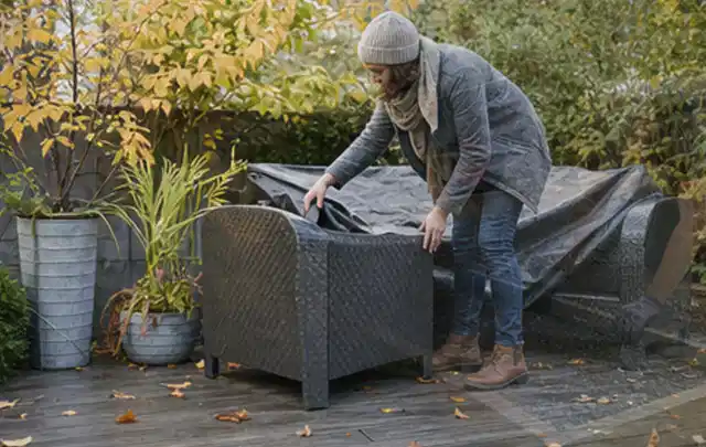 Person deckt Gartenmöbel vor der kalten Jahreszeit sorgfältig ab; Thema Gartentische, Schwerpunkt Outdoor Freizeit; Kontrolle.