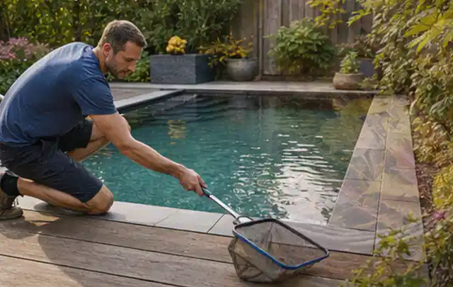 Person entfernt Blätter mit einem Kescher aus einem kleinen Gartenpool; Thema Gartentische, Schwerpunkt Reparatur; Praxisalltag.