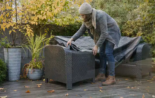 Person deckt Gartenmöbel vor der kalten Jahreszeit sorgfältig ab; Thema Gartentische, Schwerpunkt Testkriterien; Ergebnis.