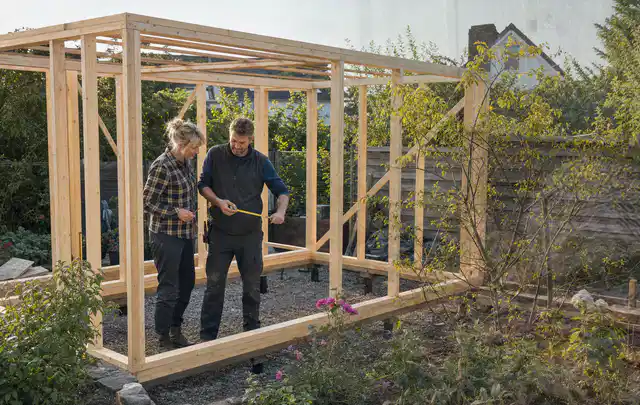 Person plant den Bau eines Gartenhauses auf einer vorbereiteten Fläche; Thema Gartenwerkstatt, Schwerpunkt Aufbau; Ergebnis.