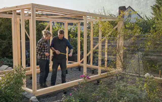 Person plant den Bau eines Gartenhauses auf einer vorbereiteten Fläche; Thema Gartenwerkstatt, Schwerpunkt Checkliste; Kontrolle.