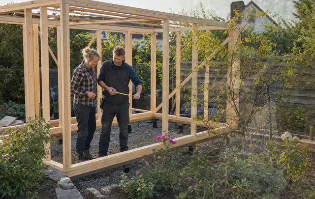 Person plant den Bau eines Gartenhauses auf einer vorbereiteten Fläche; Thema Gartenwerkstatt, Schwerpunkt Gestaltung; Kontrolle.