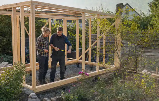 Person plant den Bau eines Gartenhauses auf einer vorbereiteten Fläche; Thema Gartenwerkstatt, Schwerpunkt Kosten; Ausgangslage.