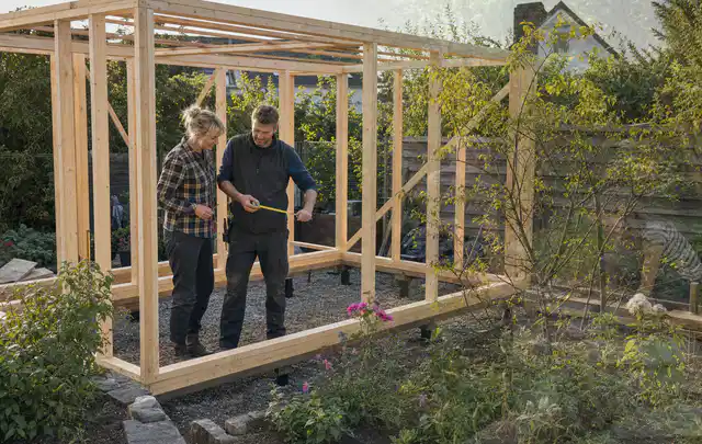 Person plant den Bau eines Gartenhauses auf einer vorbereiteten Fläche; Thema Gartenwerkstatt, Schwerpunkt Nachhaltigkeit; Ergebnis.