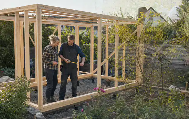 Person plant den Bau eines Gartenhauses auf einer vorbereiteten Fläche; Thema Gartenwerkstatt, Schwerpunkt Winterschutz; Praxisalltag.