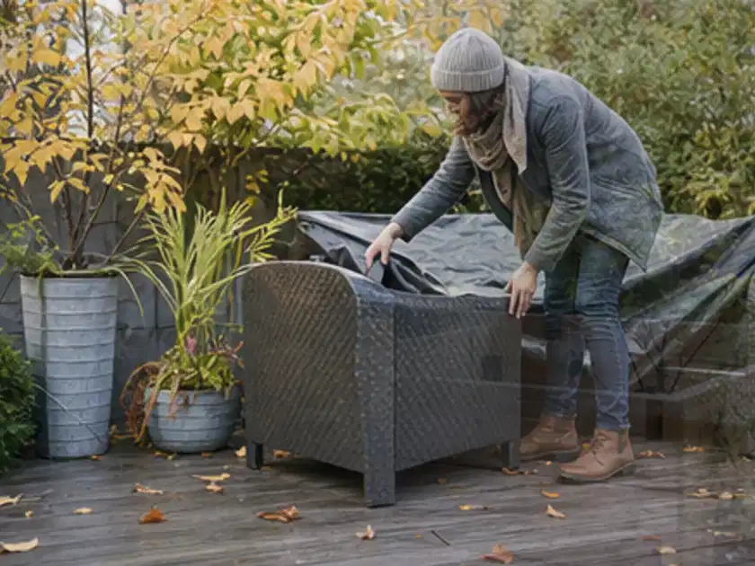 Person deckt Gartenmöbel vor der kalten Jahreszeit sorgfältig ab; Thema Gasgrills, Schwerpunkt Ersatzteile; Titelbild.