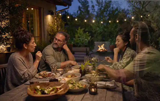 Menschen verbringen einen ruhigen Abend an einem Sitzplatz im Garten; Thema Gasgrills, Schwerpunkt Ersatzteile; Umsetzung.