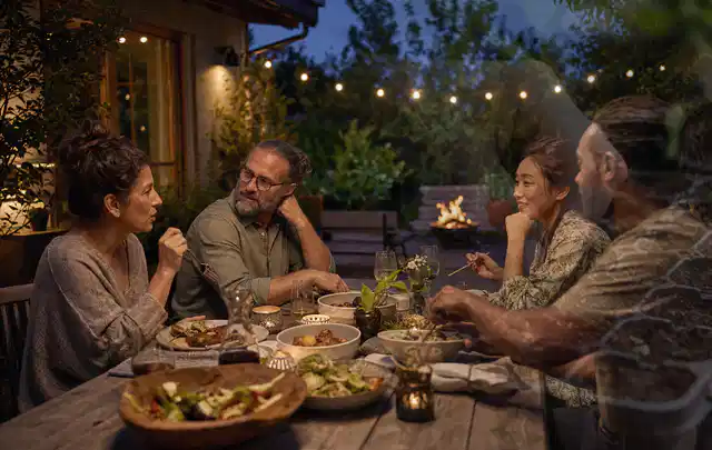 Menschen verbringen einen ruhigen Abend an einem Sitzplatz im Garten; Thema Gasgrills, Schwerpunkt Gärten mit kleiner Fläche; Ergebnis.