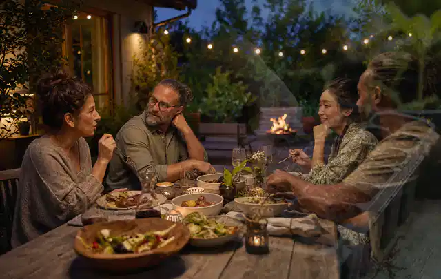 Menschen verbringen einen ruhigen Abend an einem Sitzplatz im Garten; Thema Gasgrills, Schwerpunkt Leistung; Ausgangslage.