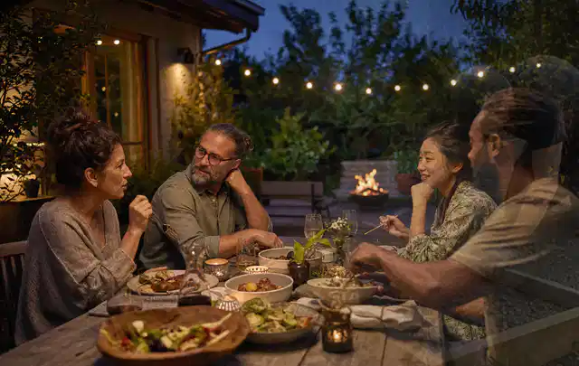 Menschen verbringen einen ruhigen Abend an einem Sitzplatz im Garten; Thema Gasgrills, Schwerpunkt Sicherheit; Praxisalltag.