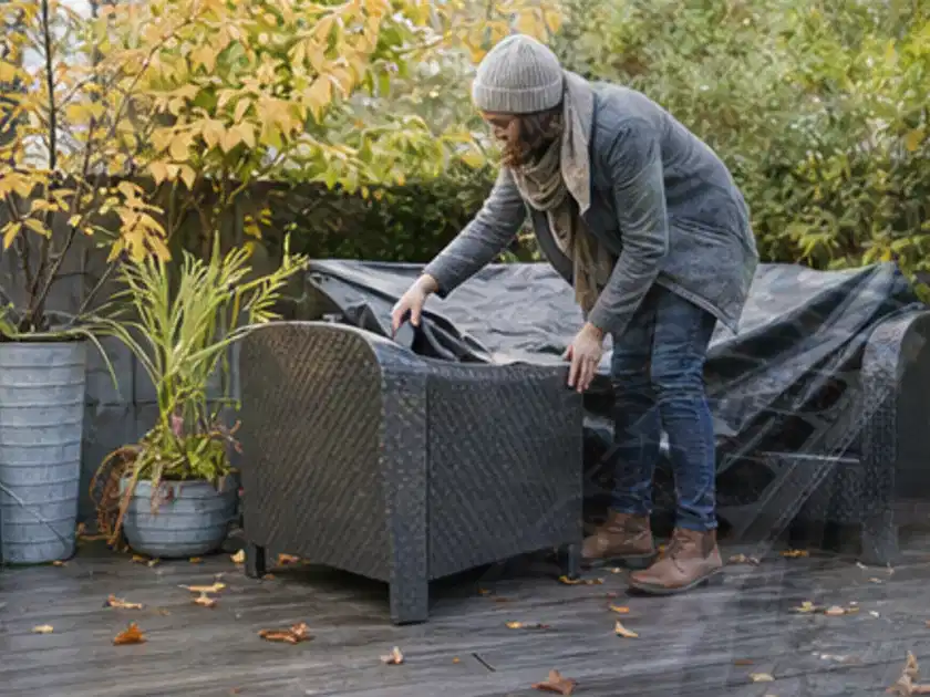 Person deckt Gartenmöbel vor der kalten Jahreszeit sorgfältig ab; Thema Gasgrills, Schwerpunkt Testkriterien; Titelbild.