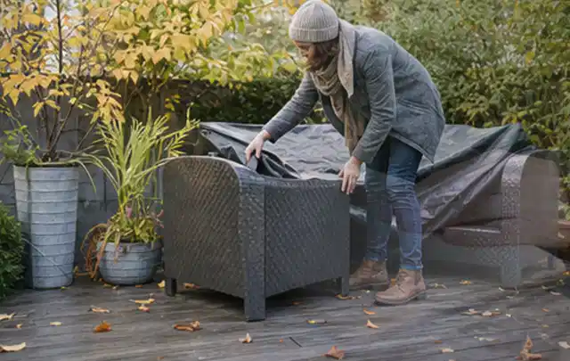 Person deckt Gartenmöbel vor der kalten Jahreszeit sorgfältig ab; Thema Gasgrills, Schwerpunkt Vergleich; Ausgangslage.