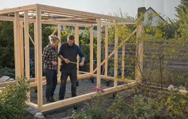 Person plant den Bau eines Gartenhauses auf einer vorbereiteten Fläche; Thema Geräteschuppen, Schwerpunkt Dimensionierung; Umsetzung.